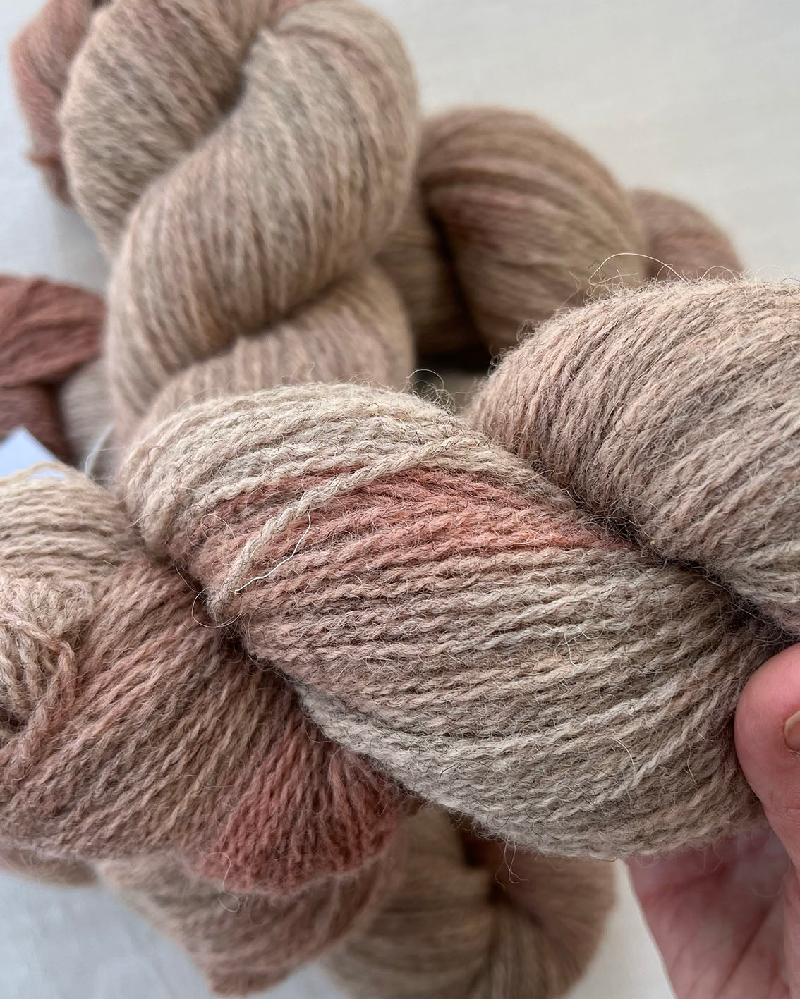Skeins of soft pink toned sustainable British 4ply wool naturally dyed with plants for knitting