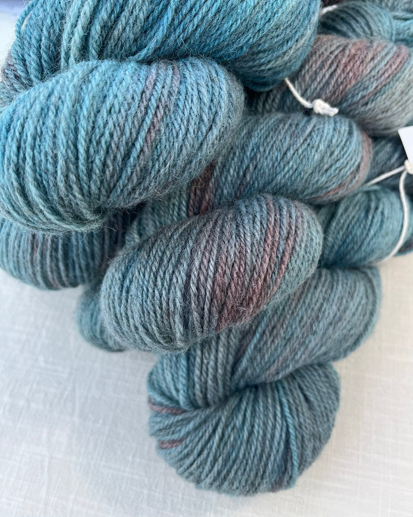 Skeins of soft blue and pink toned variegated sustainable British DK wool naturally dyed with plants