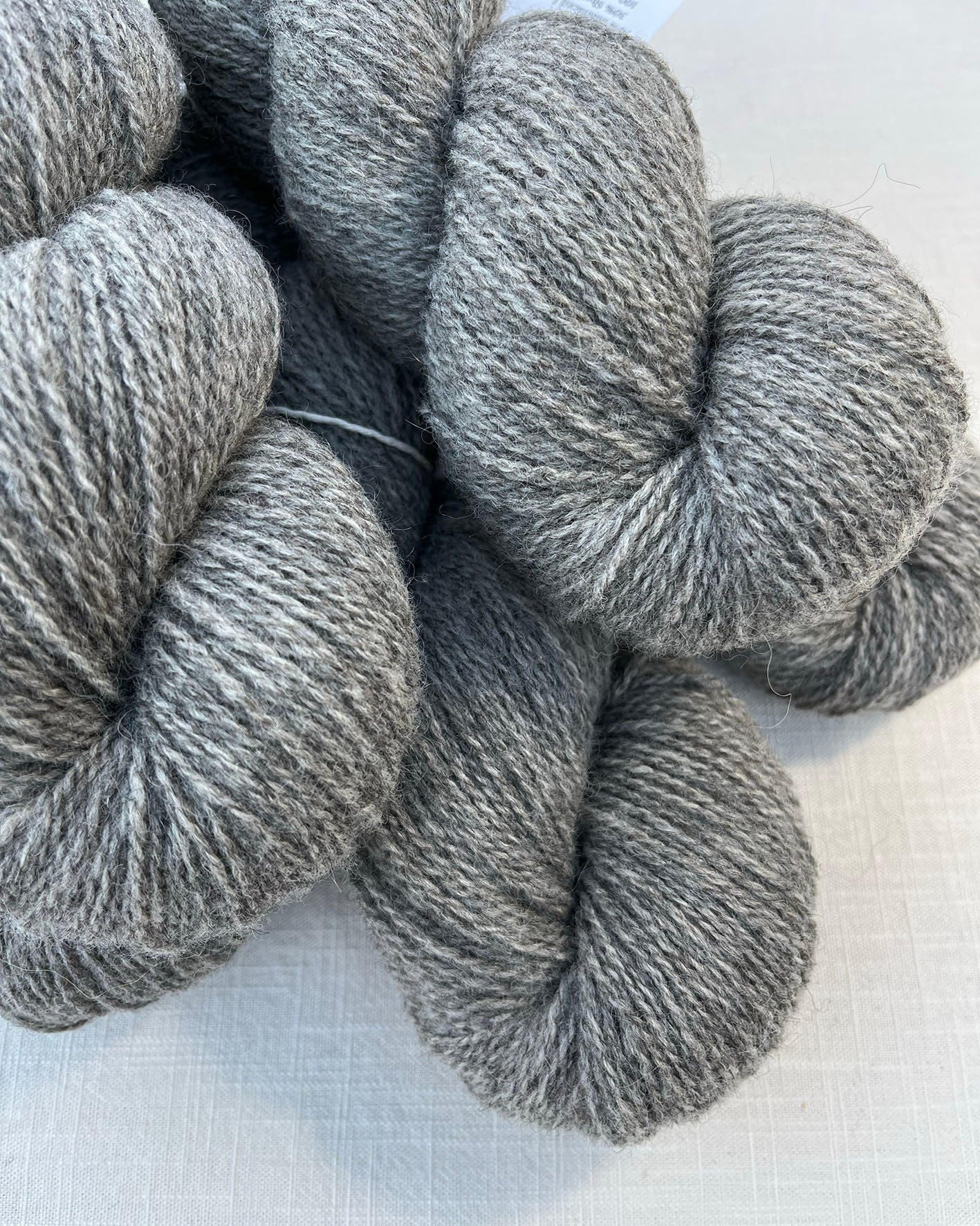 Skeins of soft graphite grey toned sustainable British Shetland 4ply wool naturally dyed with plants
