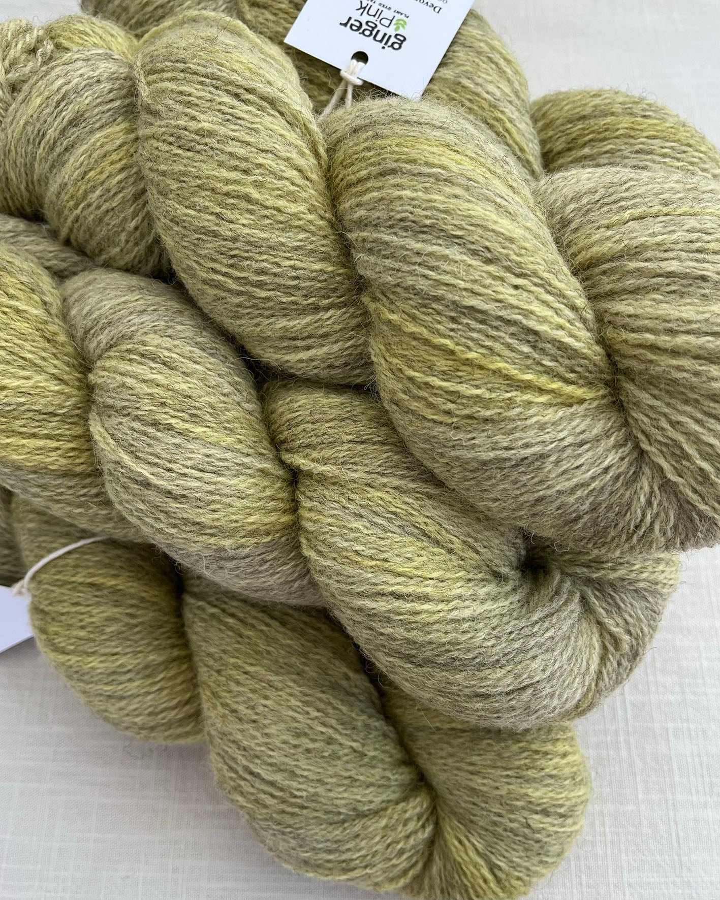 Skeins of soft green and yellow toned sustainable British 4ply wool naturally dyed with plants for knitting