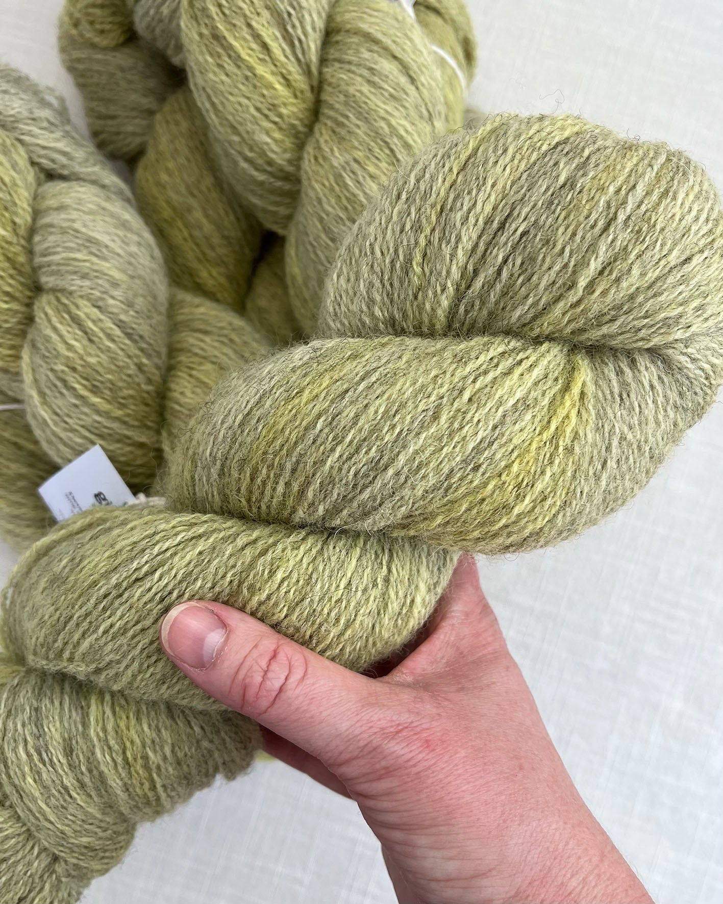 Skeins of soft green and yellow toned sustainable British 4ply wool naturally dyed with plants for knitting