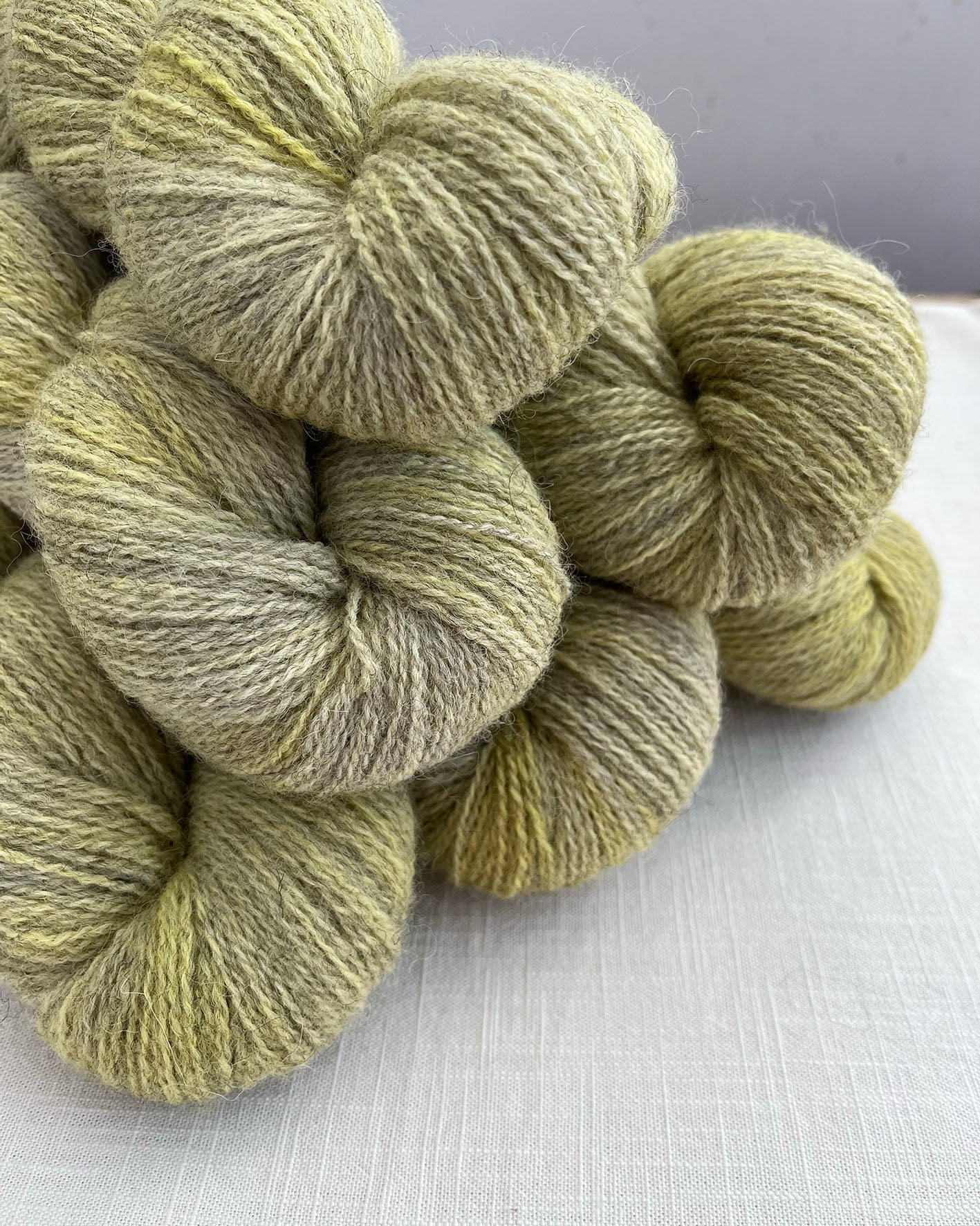 Skeins of soft green and yellow toned sustainable British 4ply wool naturally dyed with plants for knitting