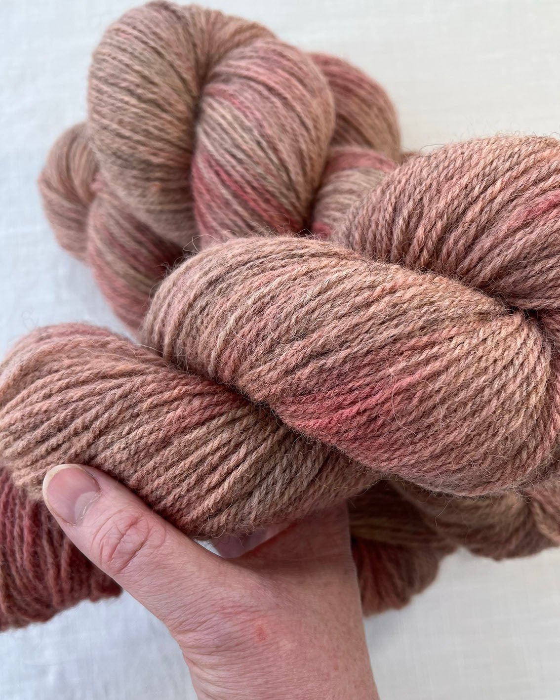 Skeins of soft pink toned semi-solid sustainable British DK wool naturally dyed with plants for knitting